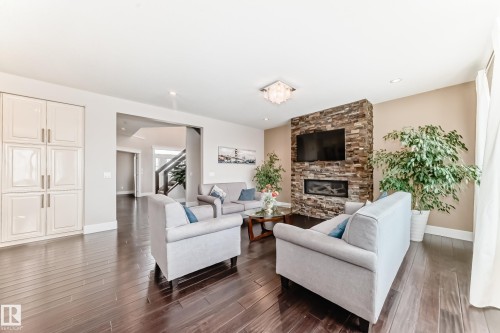 Spacious living area featuring hardwood floors, a stone-clad fireplace, and recessed lighting - 4134 Charles Link, Edmonton, AB - Indoor Photo Showing Living Room With Fireplace