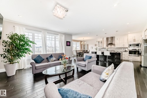 Open-concept living area with dark hardwood floors and large windows - 4134 Charles Link, Edmonton, AB - Indoor Photo Showing Living Room
