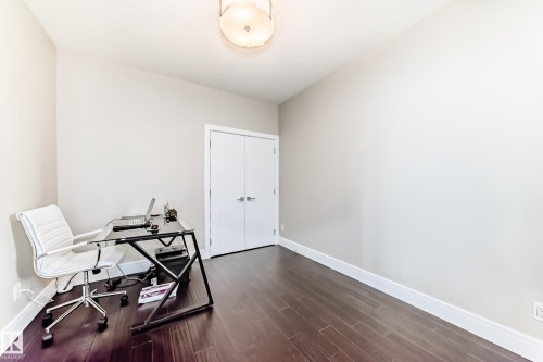 This room features dark hardwood flooring, light-colored walls, and a ceiling light fixture - 4134 Charles Link, Edmonton, AB - Indoor Photo Showing Other Room