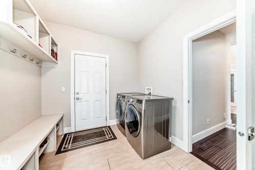 This area features a built-in bench with storage, overhead shelving with hooks, and space for laundry appliances - 4134 Charles Link, Edmonton, AB - Indoor Photo Showing Laundry Room