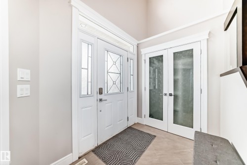 The property features a white front door with decorative glass inserts and sidelights - 4134 Charles Link, Edmonton, AB - Indoor Photo Showing Other Room