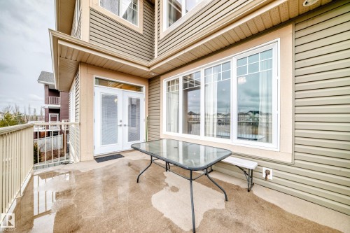 This property features a private outdoor patio with a concrete surface, a white picket railing, and glass double doors - 4134 Charles Link, Edmonton, AB - Outdoor With Deck Patio Veranda With Exterior