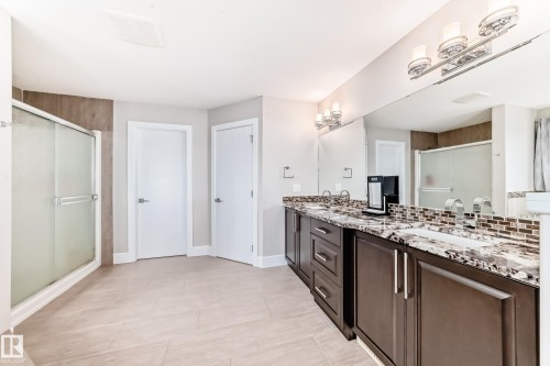 The bathroom features a dual vanity with dark wood cabinetry, a granite countertop, and mosaic tile backsplash - 4134 Charles Link, Edmonton, AB - Indoor