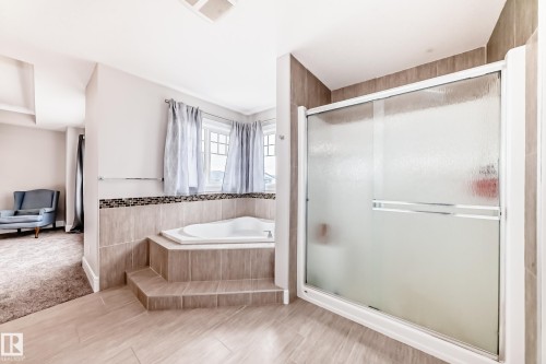 Bathroom featuring a glass-enclosed shower, a built-in bathtub with tiled surround, and tiled floors - 4134 Charles Link, Edmonton, AB - Indoor Photo Showing Bathroom