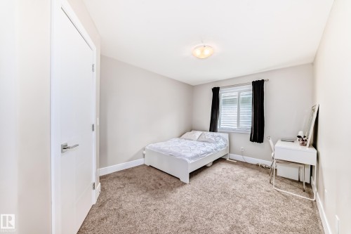 The room features light-colored walls, carpeted flooring, and a window with blinds and dark curtains - 4134 Charles Link, Edmonton, AB - Indoor Photo Showing Bedroom