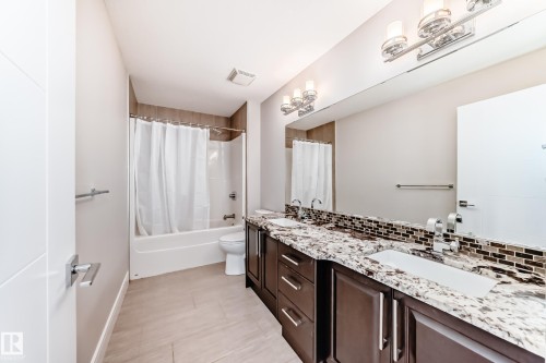 Bathroom featuring a double vanity with granite countertops, dual sinks, and dark wood cabinetry - 4134 Charles Link, Edmonton, AB - Indoor Photo Showing Bathroom