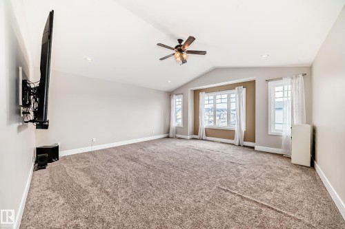 Spacious room featuring vaulted ceilings, recessed lighting, a ceiling fan, and large windows with white trim - 4134 Charles Link, Edmonton, AB - Indoor Photo Showing Other Room