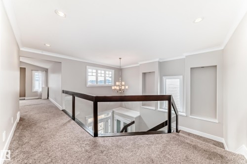 The property features an open landing with carpeted flooring, a dark wood and glass railing, and recessed lighting - 4134 Charles Link, Edmonton, AB - Indoor