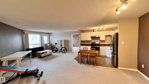 Open-concept living space featuring carpeted flooring in the living area and tiled flooring in the kitchen - 1318 330 Clareview Station Drive Nw, Edmonton, AB - Indoor