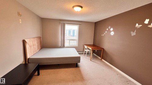 This bedroom features a window providing natural light, carpeted flooring, and a ceiling light fixture - 1318 330 Clareview Station Drive Nw, Edmonton, AB - Indoor