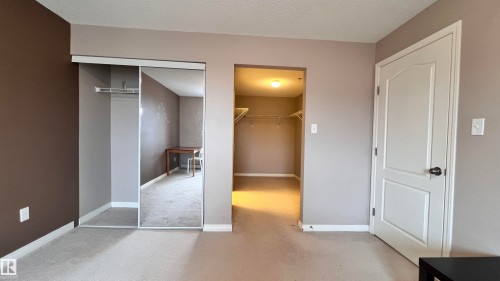The property features a spacious room with carpeted flooring, a mirrored closet, and a separate walk-in closet with wire shelving - 1318 330 Clareview Station Drive Nw, Edmonton, AB - Indoor Photo Showing Other Room