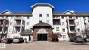 The property features a multi-story building with a light-colored facade and a prominent stone-clad entrance - 1318 330 Clareview Station Drive Nw, Edmonton, AB  - Outdoor With Facade 