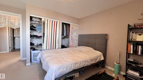 This room features neutral-toned walls, carpeting, and two closets with bi-fold doors - 1318 330 Clareview Station Drive Nw, Edmonton, AB - Indoor Photo Showing Bedroom