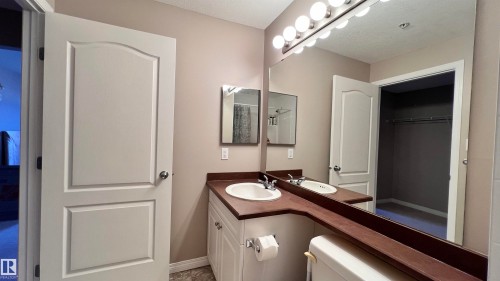 Bathroom vanity featuring a single sink, built-in storage cabinets, and a large mirror with integrated lighting - 1318 330 Clareview Station Drive Nw, Edmonton, AB - Indoor Photo Showing Bathroom