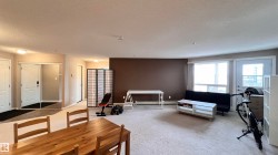 This open-plan living area features light-colored carpeting and a feature wall with a contrasting brown paint finish - 