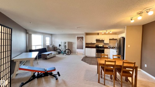 Open concept living space featuring a kitchen with white cabinetry and stainless steel appliances, and a dining area with track lighting - 1318 330 Clareview Station Drive Nw, Edmonton, AB - Indoor