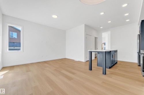 Open concept living space featuring light hardwood flooring, recessed lighting, and a kitchen island with a light countertop and a gold-toned faucet - 57 710 Mattson Drive, Edmonton, AB - Indoor