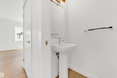 Bathroom featuring a pedestal sink with a chrome faucet, a mirror, and a towel bar - 57 710 Mattson Drive, Edmonton, AB - Indoor Photo Showing Bathroom