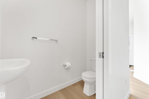 Bathroom featuring a white pedestal sink, a toilet, and light-toned flooring - 57 710 Mattson Drive, Edmonton, AB - Indoor Photo Showing Bathroom