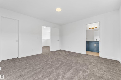 Spacious room featuring neutral grey carpeting, white walls, and a ceiling light fixture - 57 710 Mattson Drive, Edmonton, AB - Indoor Photo Showing Other Room