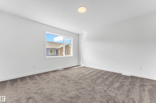 This room features a window providing natural light, white walls, white trim, and gray carpet - 57 710 Mattson Drive, Edmonton, AB - Indoor Photo Showing Other Room