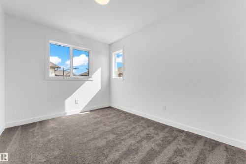 This room offers abundant natural light through its two windows, illuminating the light-colored walls and grey carpet - 57 710 Mattson Drive, Edmonton, AB - Indoor Photo Showing Other Room