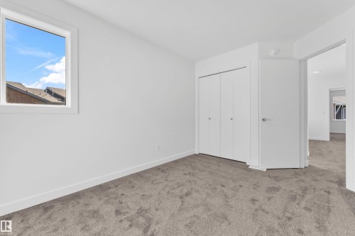 This room features neutral-toned carpeting, white walls, and a window providing natural light - 57 710 Mattson Drive, Edmonton, AB - Indoor Photo Showing Other Room