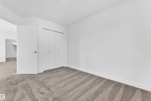 The property features a room with light-colored carpeting, white walls, and a white door with a silver handle - 57 710 Mattson Drive, Edmonton, AB - Indoor Photo Showing Other Room