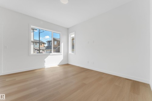 Spacious room featuring light-toned wood flooring, crisp white walls, and a large window providing natural illumination - 57 710 Mattson Drive, Edmonton, AB - Indoor Photo Showing Other Room
