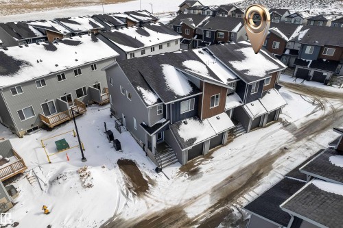 This property features a contemporary exterior design with a combination of grey and brown siding, dark roofs, and individual garage doors - 57 710 Mattson Drive, Edmonton, AB - Outdoor