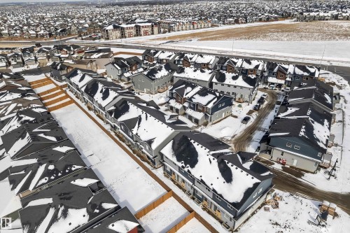 Aerial view showcasing a community of homes with dark roofs and light-colored siding, set against a snow-covered landscape - 57 710 Mattson Drive, Edmonton, AB -  With View
