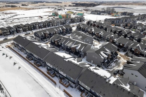 This property is located in a residential area, featuring a collection of townhomes with dark gray roofs and light-colored siding - 57 710 Mattson Drive, Edmonton, AB - Outdoor With View