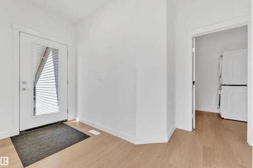 Entryway with light hardwood style flooring and a white door featuring a large glass panel - 57 710 Mattson Drive, Edmonton, AB - Indoor Photo Showing Other Room