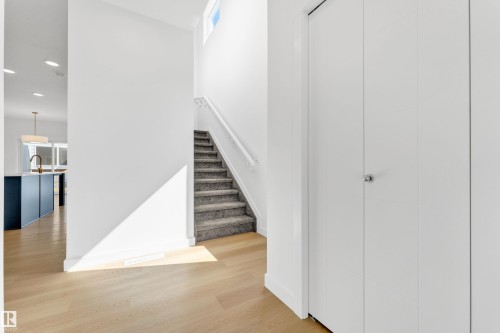 Inviting entryway featuring light wood flooring, a carpeted staircase with a white handrail, and a white bi-fold closet - 57 710 Mattson Drive, Edmonton, AB - Indoor Photo Showing Other Room