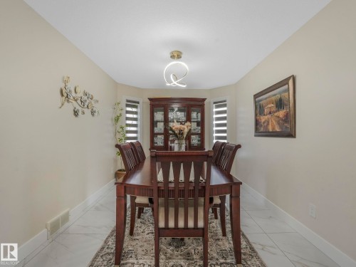 Dining area featuring light-toned walls, tiled flooring, and a modern ceiling light fixture - 1147 Lincoln Crescent, Edmonton, AB - Indoor Photo Showing Dining Room