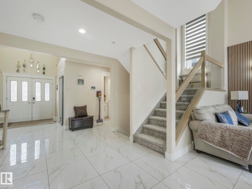 Bright and inviting entryway featuring white double doors with frosted glass panels, leading into an open living space with polished tile flooring - 1147 Lincoln Crescent, Edmonton, AB - Indoor Photo Showing Other Room