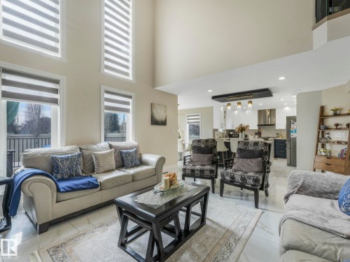 The living area features high ceilings, large windows providing natural light, and tile flooring - 1147 Lincoln Crescent, Edmonton, AB - Indoor Photo Showing Living Room