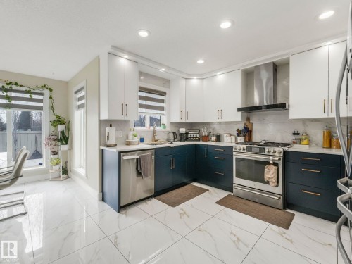 The kitchen features white upper cabinets, dark lower cabinets, and stainless steel appliances - 1147 Lincoln Crescent, Edmonton, AB - Indoor Photo Showing Kitchen With Upgraded Kitchen