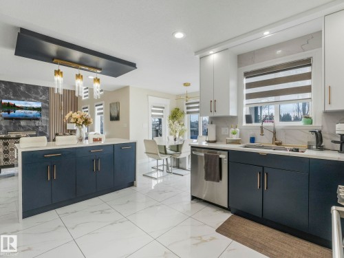 Kitchen with white tile flooring, dark blue lower cabinetry, white upper cabinetry, and light countertops - 1147 Lincoln Crescent, Edmonton, AB - Indoor Photo Showing Kitchen
