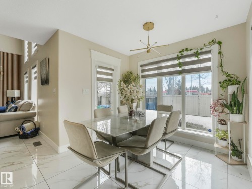 This dining area features a modern light fixture and large windows, providing abundant natural light - 1147 Lincoln Crescent, Edmonton, AB - Indoor Photo Showing Dining Room