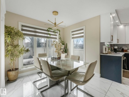 The dining area features large windows with blinds, a modern chandelier, and white tile flooring - 1147 Lincoln Crescent, Edmonton, AB - Indoor Photo Showing Dining Room