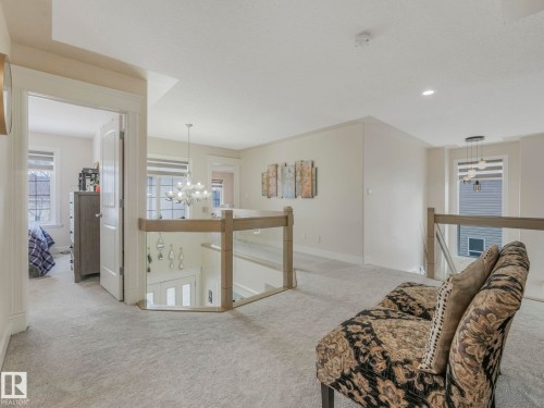 This spacious landing area features light-colored carpeting, a contemporary glass and wood railing, and recessed lighting - 1147 Lincoln Crescent, Edmonton, AB - Indoor