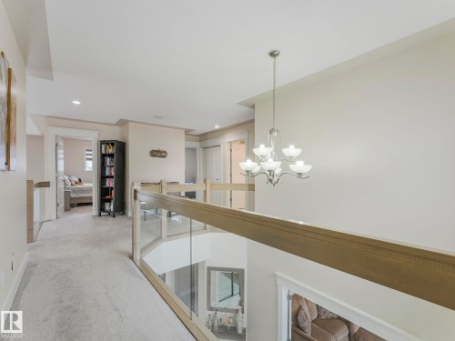 The upper landing features light-colored carpeting, recessed lighting, and a glass and wood railing overlooking the lower level - 1147 Lincoln Crescent, Edmonton, AB - Indoor Photo Showing Other Room