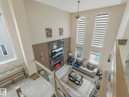 The living area features high ceilings, a contemporary fireplace, and a ceiling fan - 1147 Lincoln Crescent, Edmonton, AB - Indoor With Fireplace