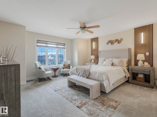 This room features light-colored walls and carpeting, a large window with blinds, and a ceiling fan - 1147 Lincoln Crescent, Edmonton, AB - Indoor Photo Showing Bedroom