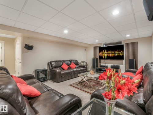 This entertainment space features recessed lighting, a large wall-mounted television, and a neutral color palette - 1147 Lincoln Crescent, Edmonton, AB - Indoor