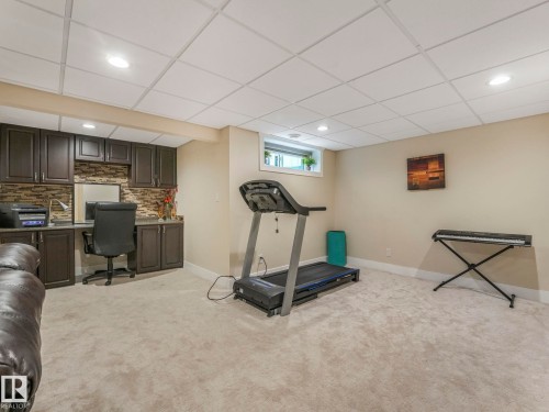 This versatile room features plush carpeting, a built-in desk area with dark cabinetry, and recessed lighting - 1147 Lincoln Crescent, Edmonton, AB - Indoor