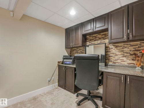 Dedicated office space featuring dark wood cabinetry, a tiled backsplash, and a light-colored countertop - 1147 Lincoln Crescent, Edmonton, AB - Indoor Photo Showing Office