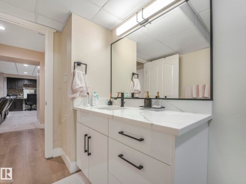 Modern vanity with a white countertop and a rectangular sink, featuring a matte black faucet and black hardware - 1147 Lincoln Crescent, Edmonton, AB - Indoor Photo Showing Bathroom