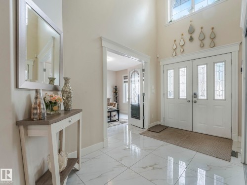 Foyer featuring white tile flooring, a double front door with decorative glass inserts, and a transom window above - 1147 Lincoln Crescent, Edmonton, AB - Indoor Photo Showing Other Room
